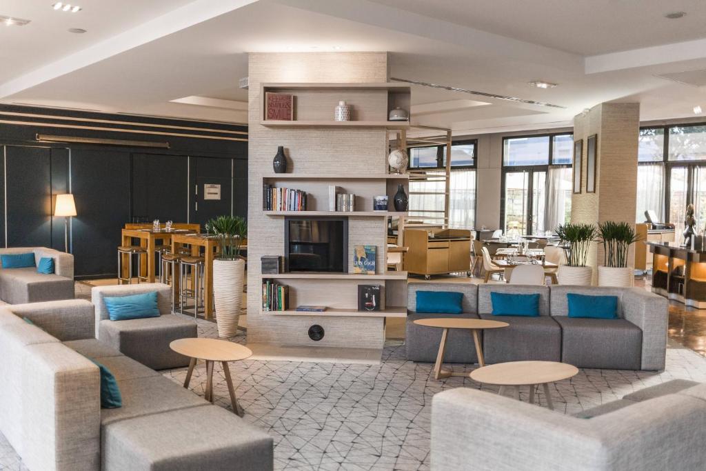 a lobby with couches and tables in a building at Courtyard by Marriott Paris La Defense West - Colombes in Colombes
