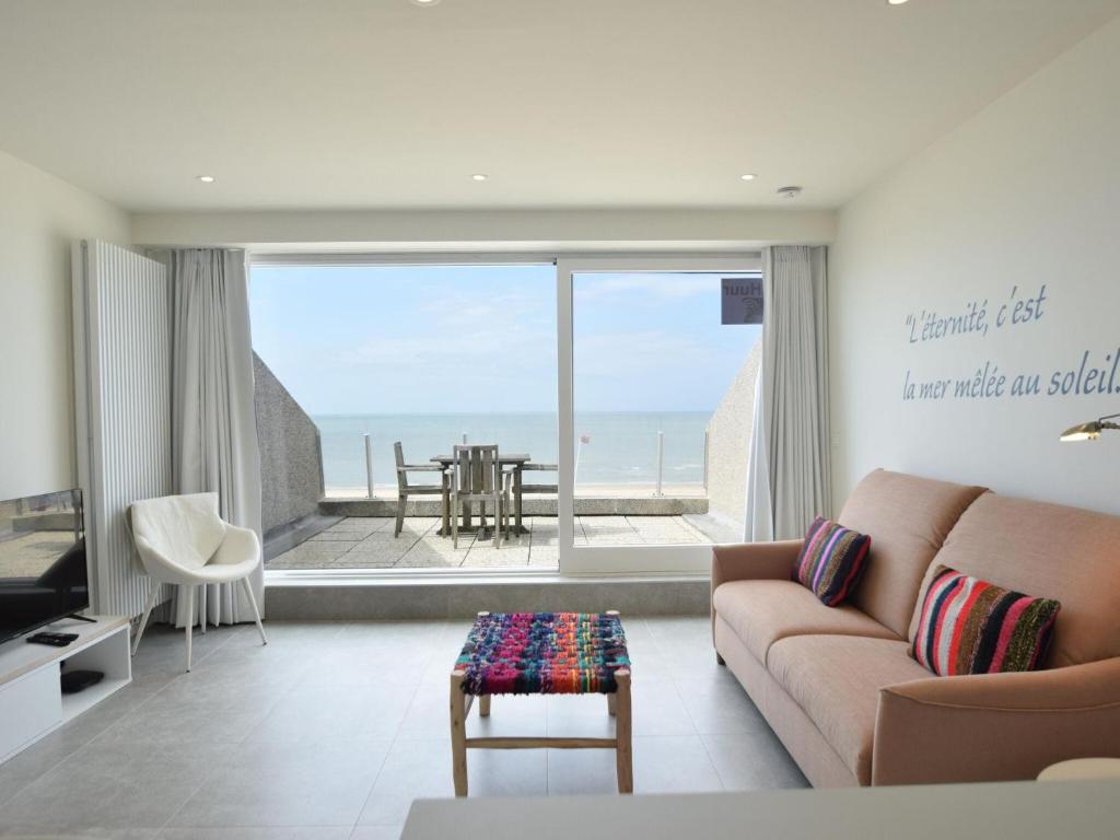 een woonkamer met een bank en uitzicht op de oceaan bij Mayfair 0205 exclusive residence with sea view in De Haan