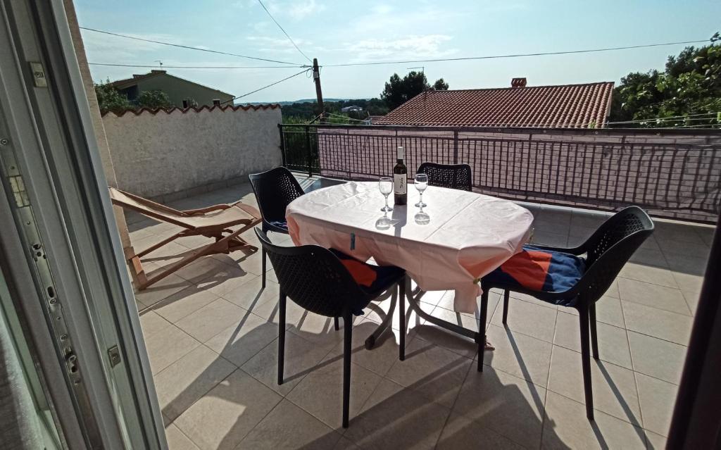 uma mesa com cadeiras e uma garrafa de vinho na varanda em Sonja Apartment em Premantura