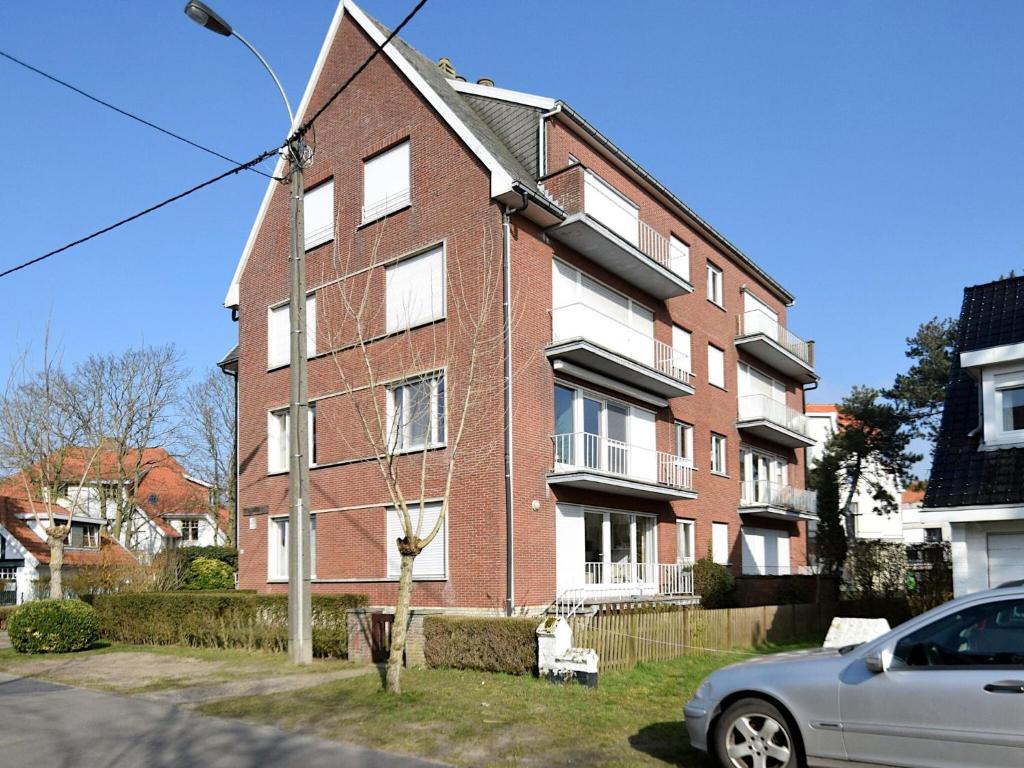 um edifício de tijolos vermelhos com um carro estacionado na frente em Dante 0103 furnished apartment with 2 bedrooms em De Haan