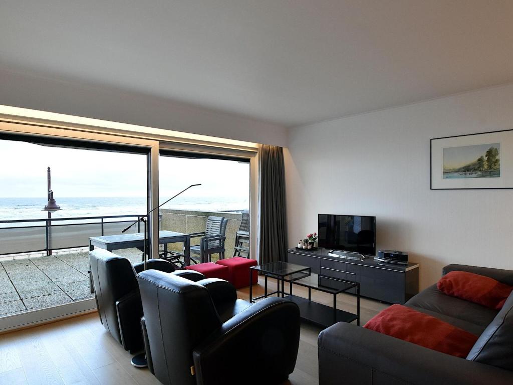 een woonkamer met een bank en stoelen en een balkon bij James Ensor 0102 south-facing corner apartment in De Haan