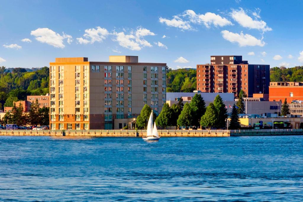 ein Segelboot im Wasser vor einer Stadt in der Unterkunft Delta Hotels by Marriott Sault Ste. Marie Waterfront in Sault Ste. Marie