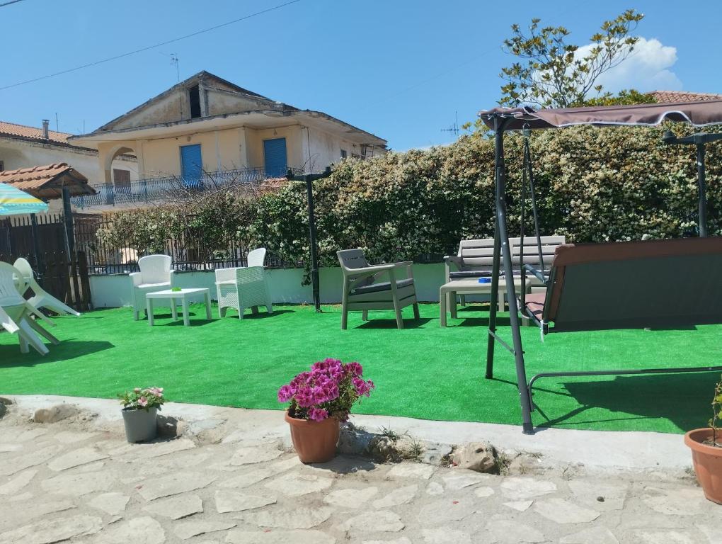 een achtertuin met een gazon met stoelen en een parasol bij Oasi hause in Castel Volturno