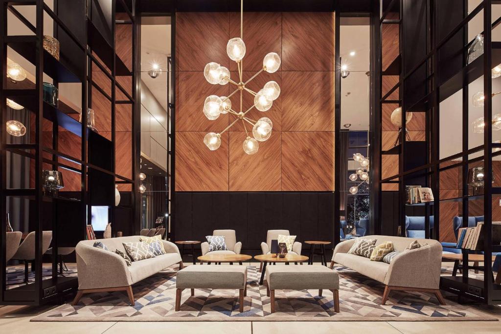 a lobby with chairs and a table and a chandelier at Courtyard by Marriott Katowice City Center in Katowice