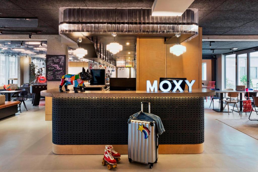 un hall d'entrée avec une valise devant un comptoir dans l'établissement Moxy Paris Bastille, à Paris