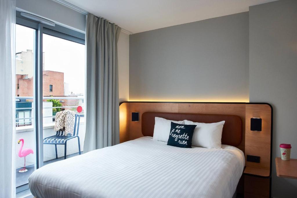 a hotel room with a bed and a balcony at Moxy Paris Bastille in Paris