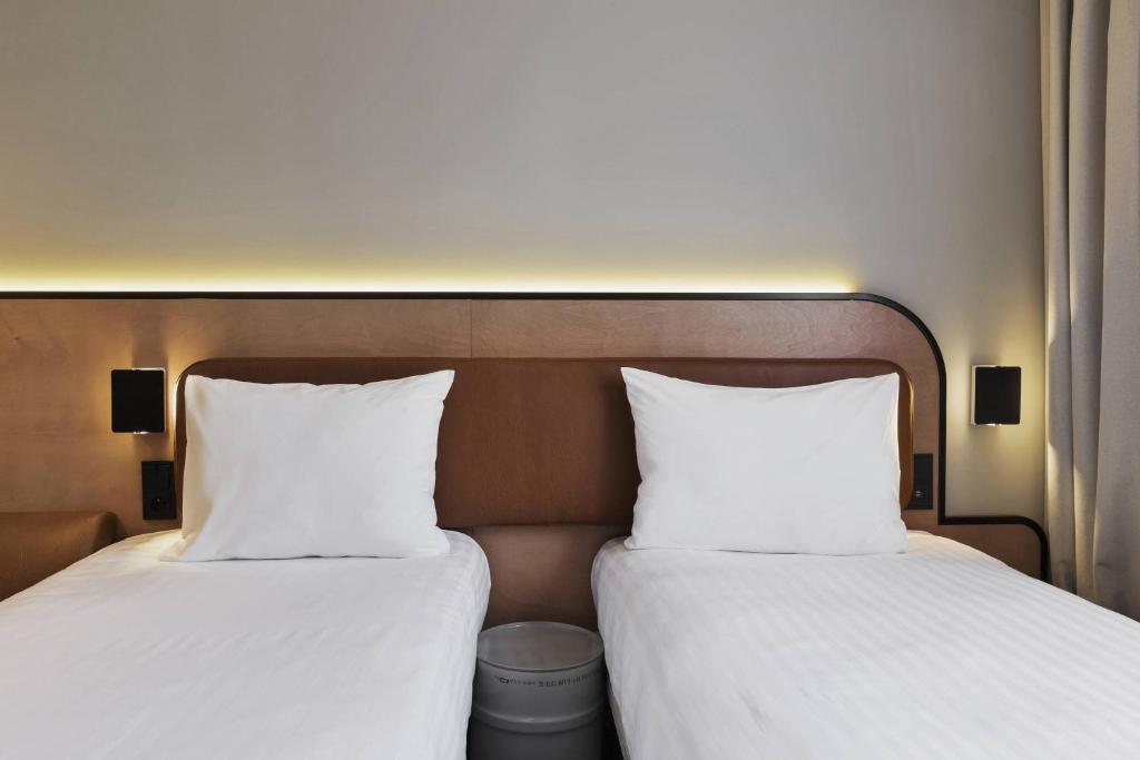 two beds with white pillows sitting next to each other at Moxy Paris Bastille in Paris