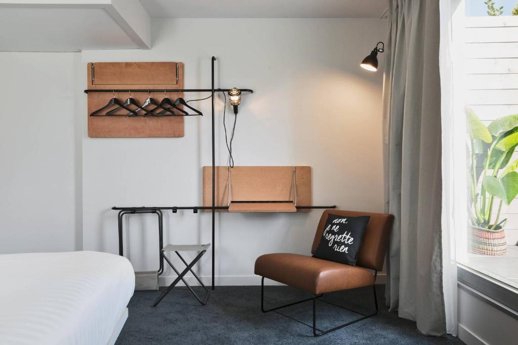 a bedroom with a bed and a chair in a room at Moxy Paris Bastille in Paris