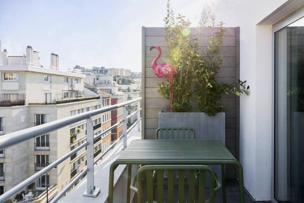 a balcony with a table and a pink flamingo on the wall at Moxy Paris Bastille in Paris