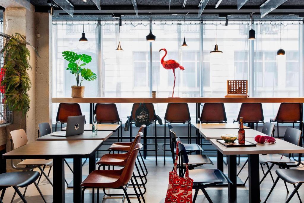 a restaurant with tables and chairs and a flamingo on the wall at Moxy Paris Bastille in Paris