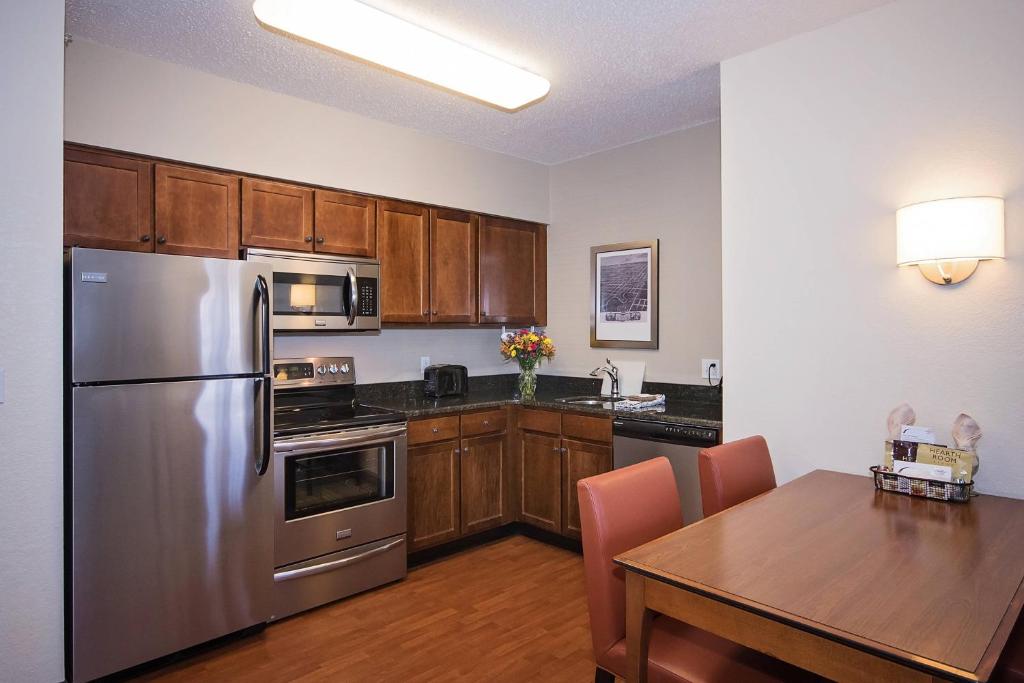 a kitchen with a table and a stainless steel refrigerator at Residence Inn Rochester Mayo Clinic Area in Rochester