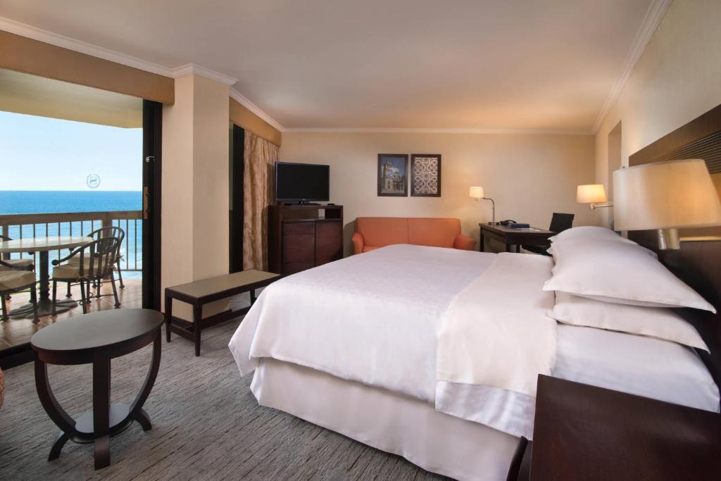 a hotel room with a large bed and a balcony at Sheraton Santo Domingo in Santo Domingo