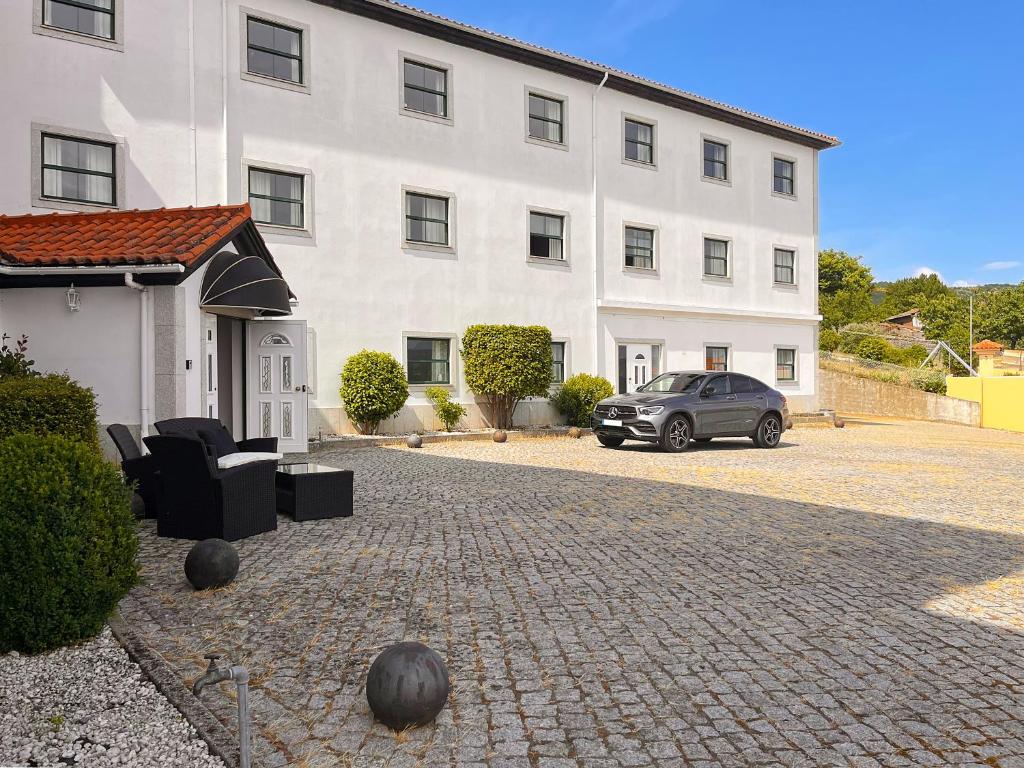Ein Auto parkte vor einem weißen Gebäude in der Unterkunft Vinhais Hotel in Vinhais