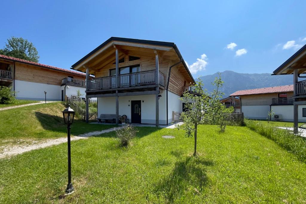 a house with a balcony and a yard with trees at Chalet Charivari Inzell mit Whirlpool, Sauna & Garten in Inzell