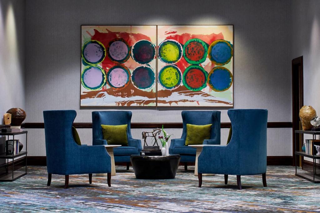 a lobby with blue chairs and a painting on the wall at Renaissance Mobile Riverview Plaza Hotel in Mobile
