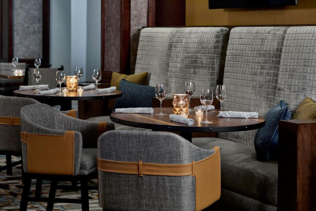 a restaurant with two tables and chairs with wine glasses at Renaissance Mobile Riverview Plaza Hotel in Mobile