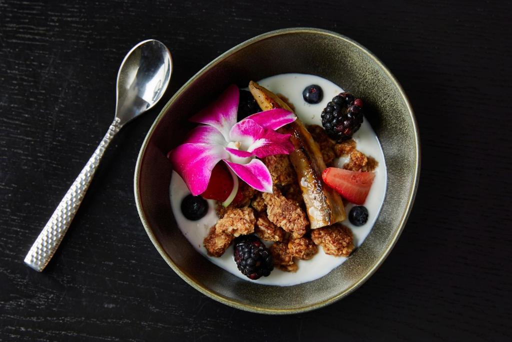 a bowl of cereal and fruit with a flower on it at Renaissance Mobile Riverview Plaza Hotel in Mobile