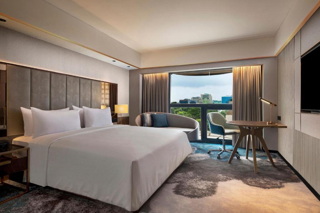 a hotel room with a bed and a desk and a window at Sari Pacific Jakarta, Autograph Collection in Jakarta