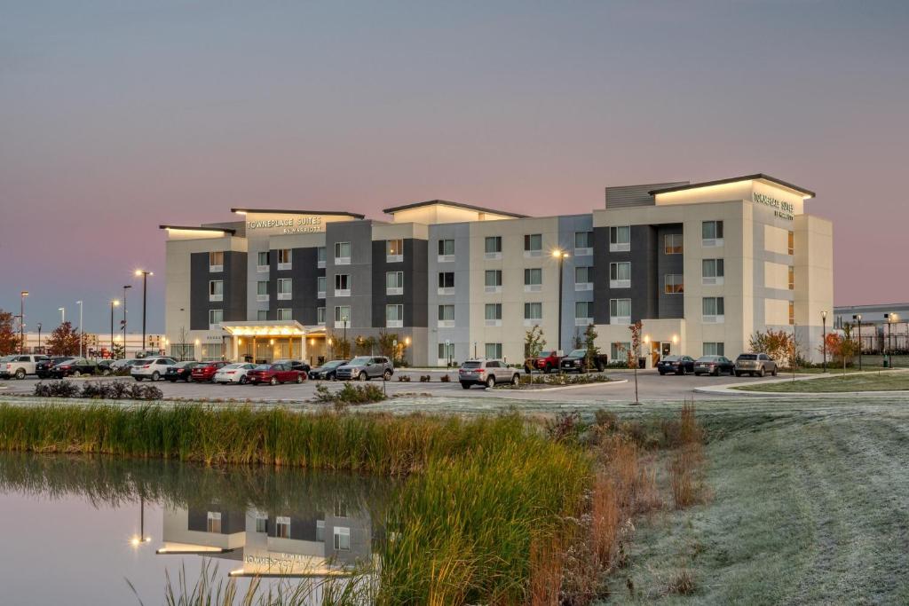 TownePlace Suites by Marriott Indianapolis Airport في انديانابوليس: مبنى كبير به سيارات تقف في موقف للسيارات