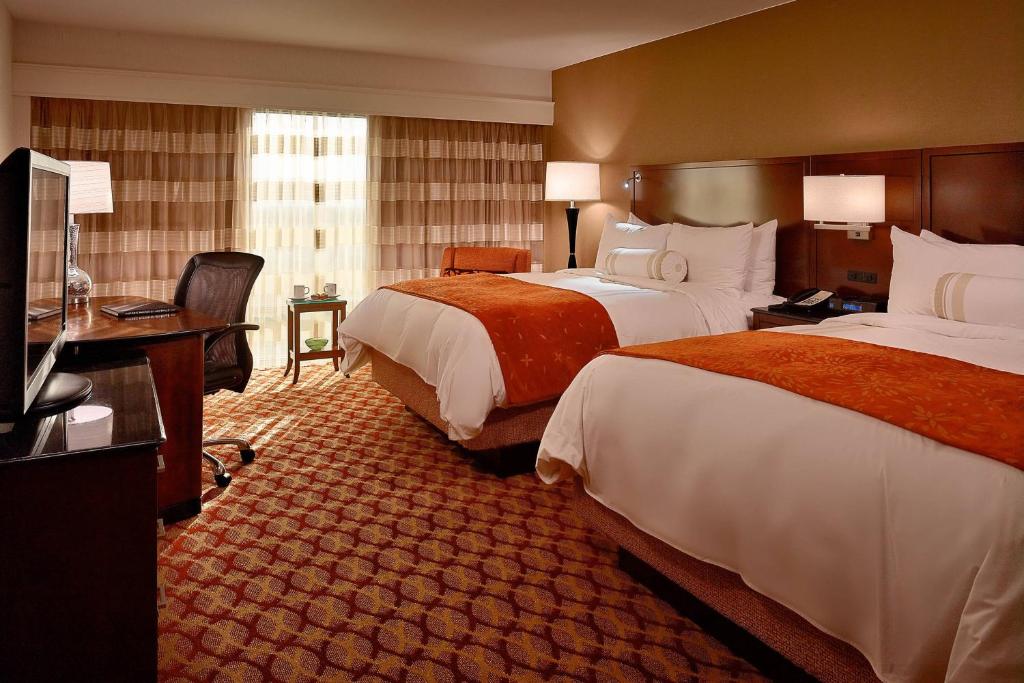 a hotel room with two beds and a television at Marriott Louisville East in Louisville