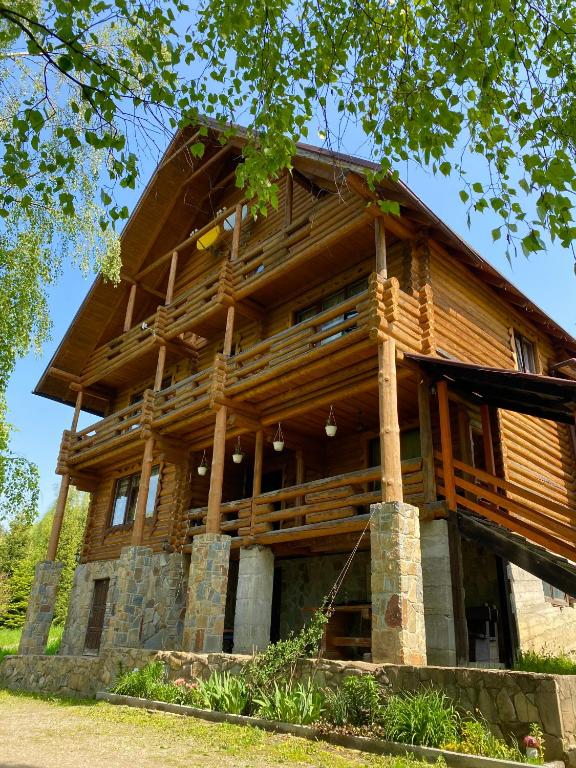 a large wooden house with a tree at Гостинний двір in Oryavchyk