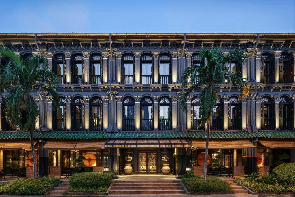 a building with palm trees in front of it at Duxton Reserve Singapore, Autograph Collection in Singapore