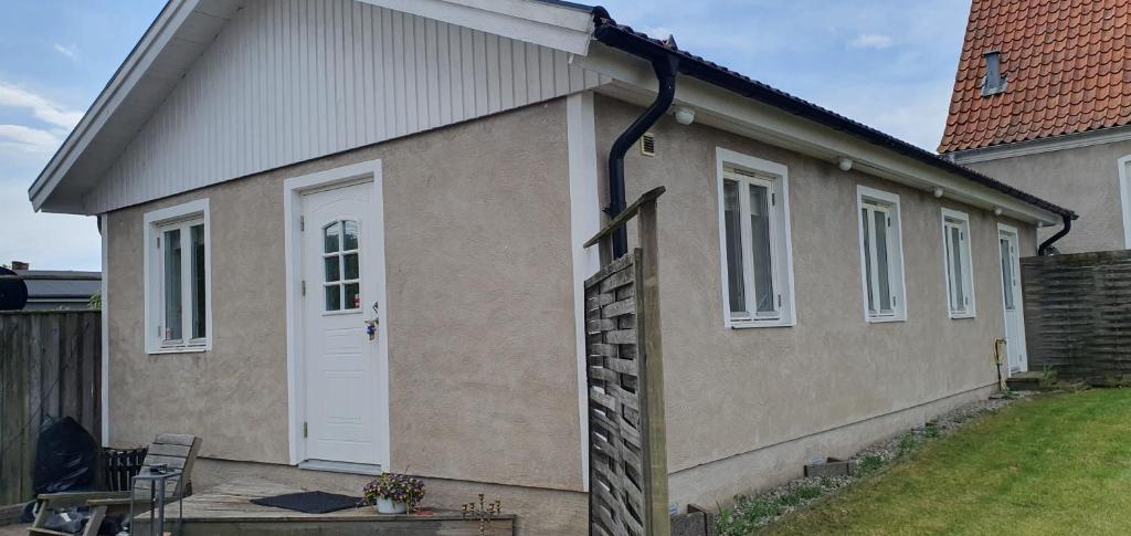 a house with a white door and a yard at Gårdshuset i Simrishamn in Simrishamn