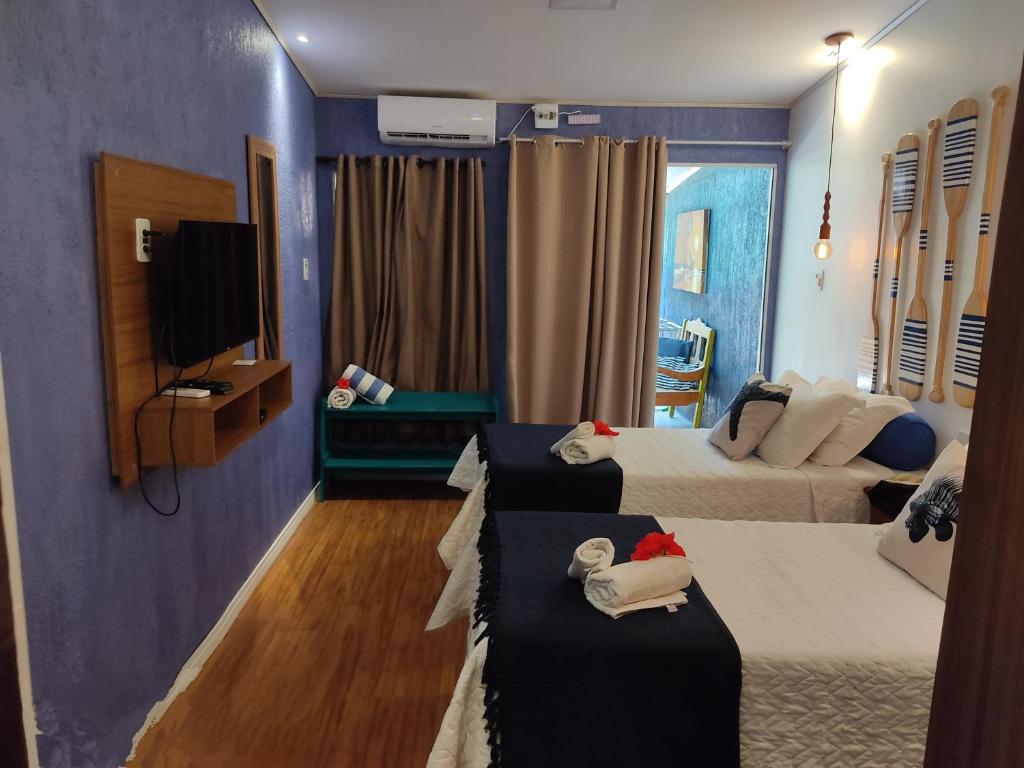um quarto de hotel com duas camas e uma televisão em Corrente Marítima Pousada em Fernando de Noronha