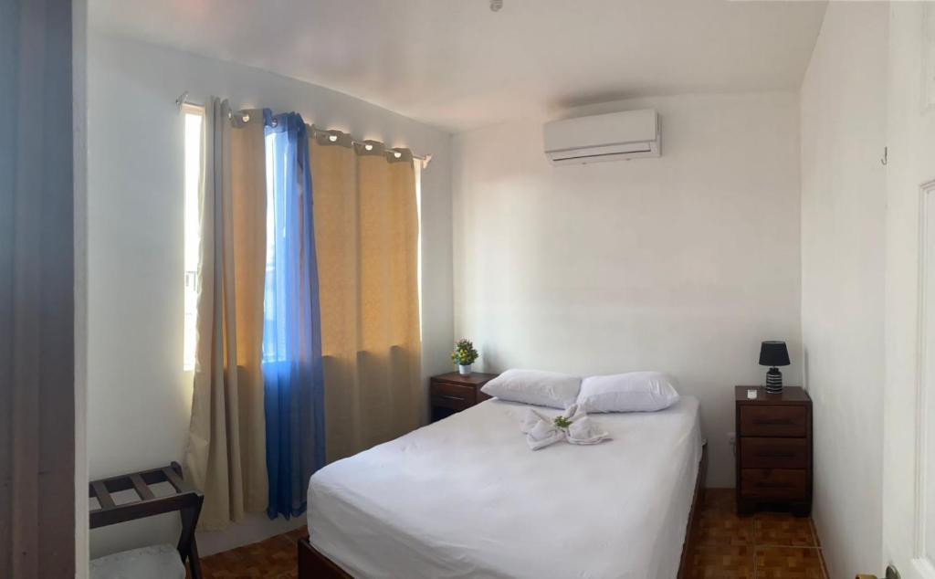 a bedroom with a white bed and a window at coati del arenal posada in Fortuna