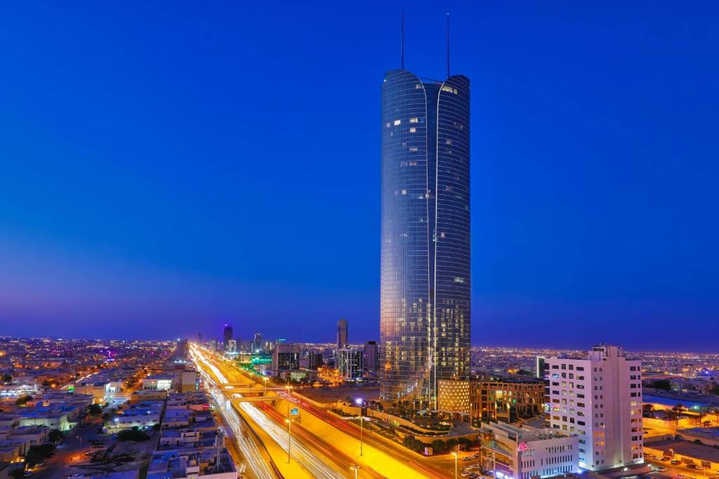 JW Marriott Hotel Riyadh في الرياض: أفق المدينة مع مبنى طويل في الليل