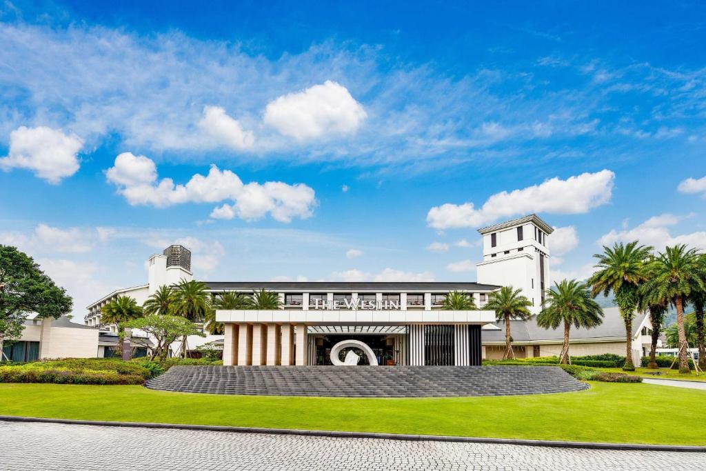 un grand bâtiment blanc avec des palmiers devant lui dans l'établissement The Westin Tashee Resort, Taoyuan, à Daxi
