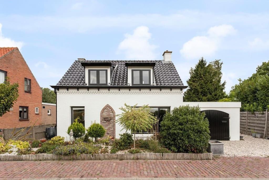 una casa blanca con techo negro en Vrijstaande woning, grote tuin., en Waterlandkerkje