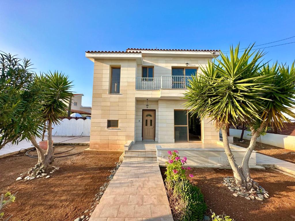 une maison avec des palmiers devant elle dans l'établissement Lovely Pool Villa in Pyla, à Pýla