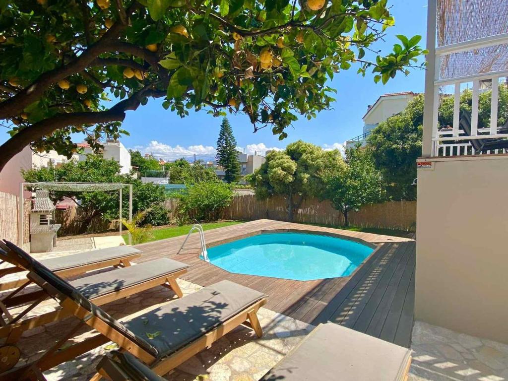 une petite piscine avec une terrasse en bois et un banc dans l'établissement Nerria's Villa, à Kalamaki