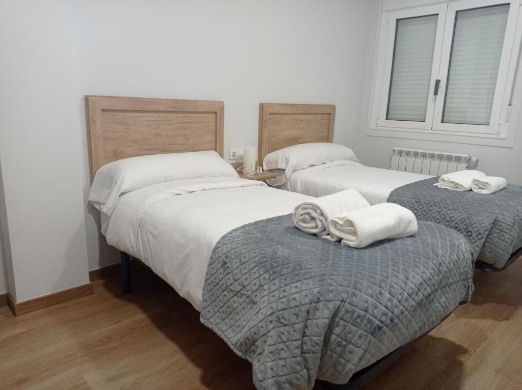 a bedroom with two beds with towels on the ottoman at Castiñeiras Street 2 in Sarria