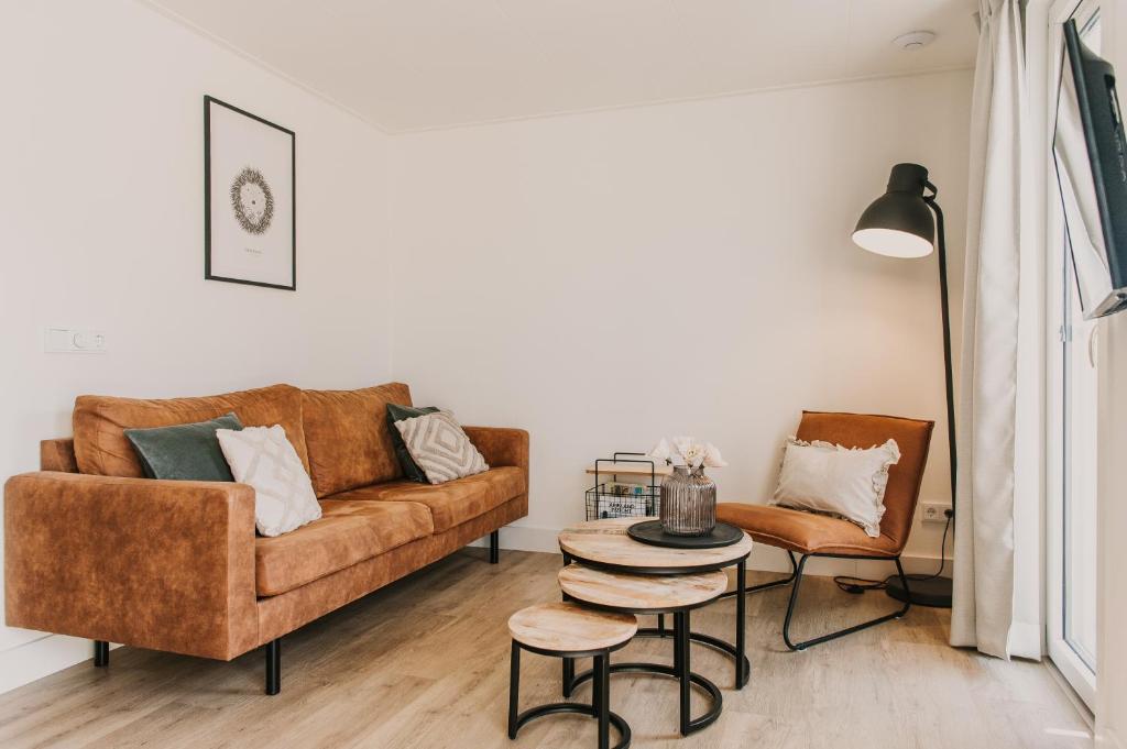 a living room with a couch and a table and chairs at Appartement Wadpier in Buren