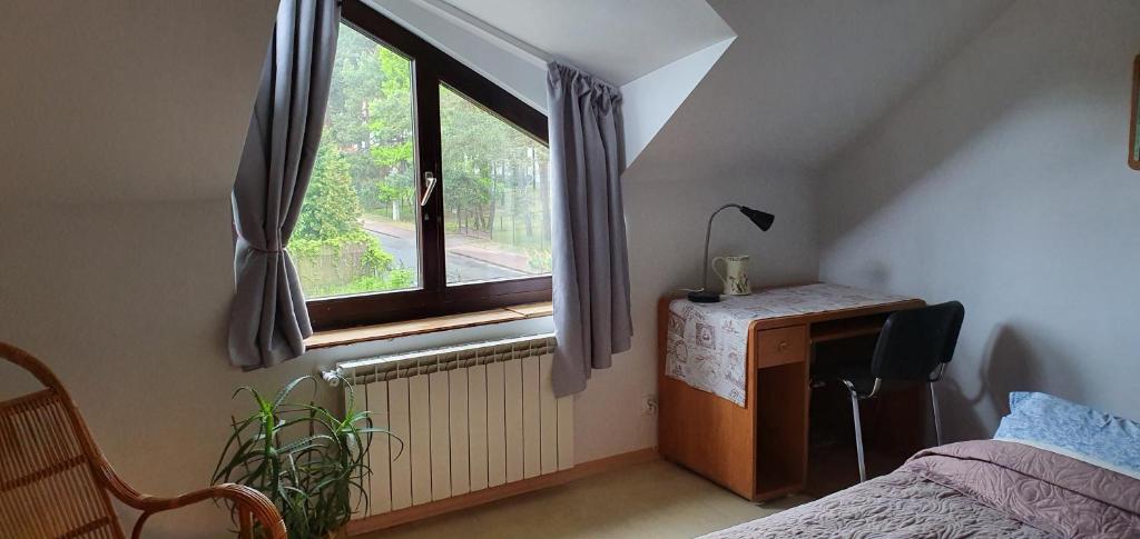 1 dormitorio con cama, escritorio y ventana en Millanova, en Milanówek