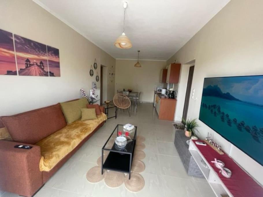 a living room with a couch and a tv at Cozy apartment Kokkoni beach in Kokóni