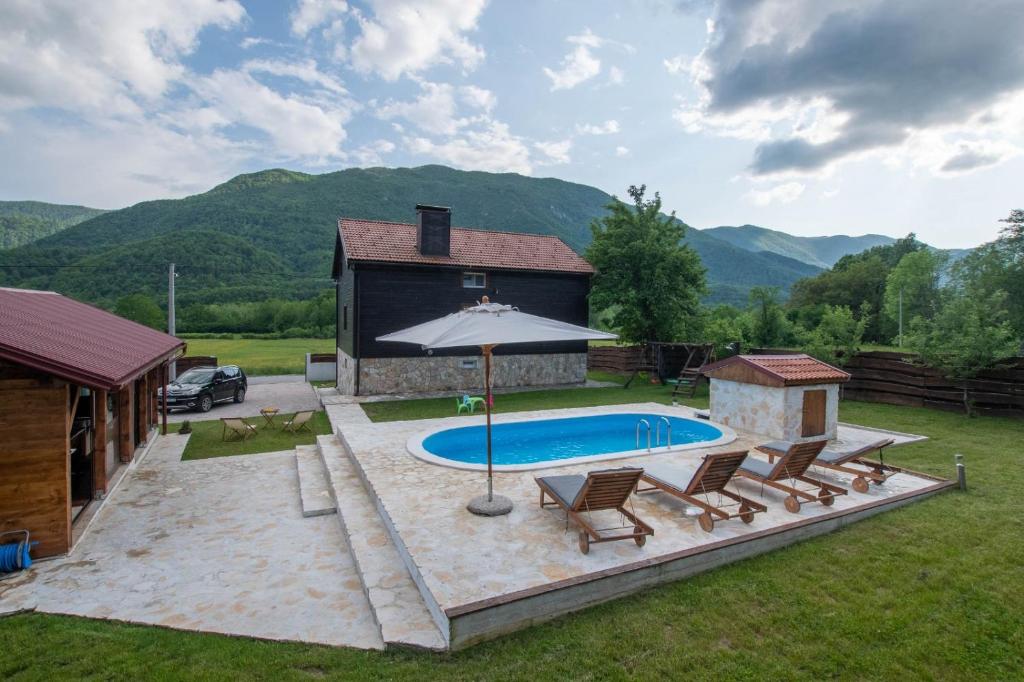 a pool with chairs and an umbrella next to a house at Holiday Home Nina with a heated pool in Brušane