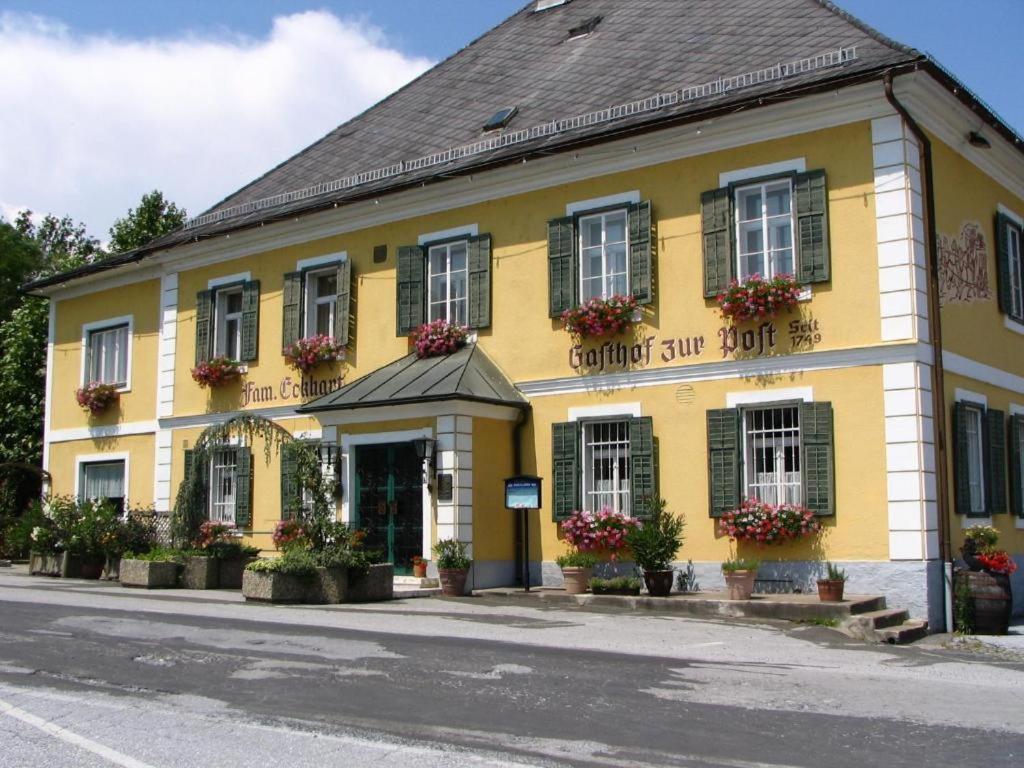a yellow building with flowers on the windows at Gasthof zur Post in Soding