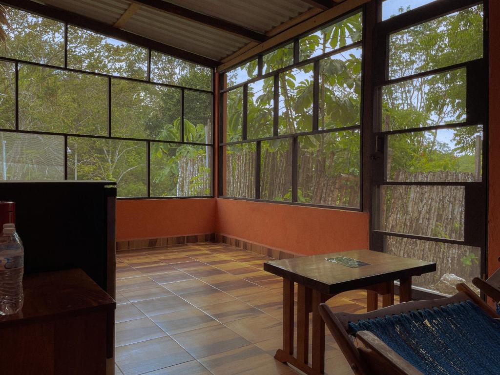 Habitación vacía con ventanas grandes y mesa. en Ecohabitat, en Xpujil