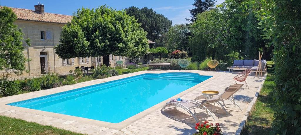 una piscina in un cortile con sedie e tavolo di Au Do'Mayne des Bouilles - Spa & Piscine a Lussac