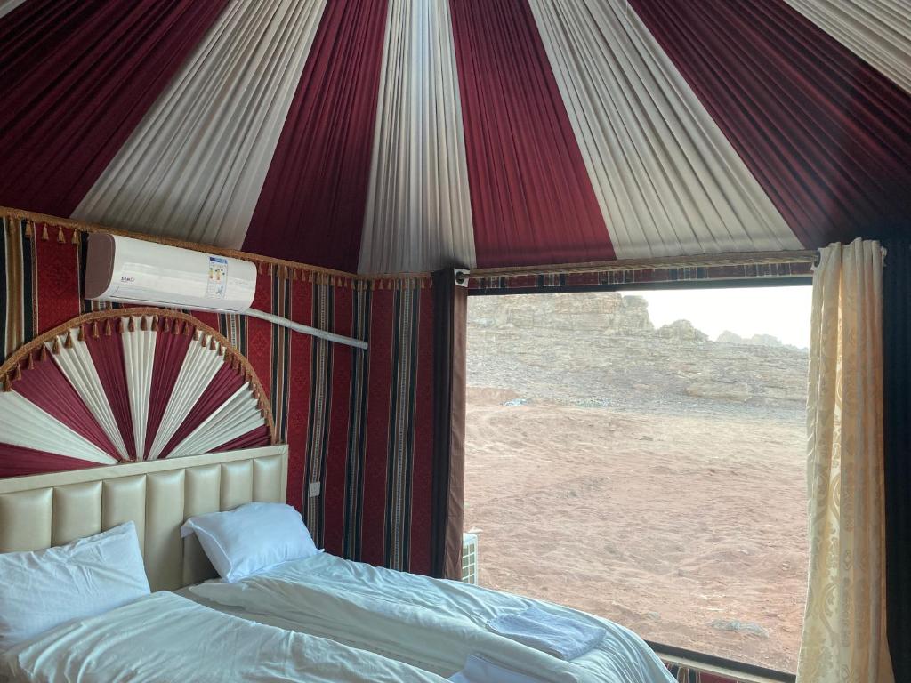 a bedroom with a tent with a bed and a window at Wadi rum Sunrise luxury camp in Wadi Rum