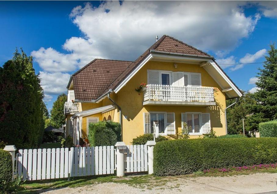 una casa gialla con una recinzione bianca davanti di GIZELLA HÁZ a Keszthely