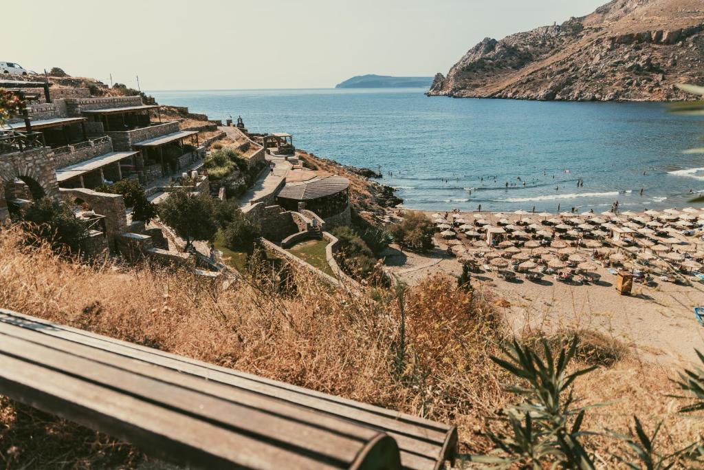 um banco numa colina ao lado de uma praia em Marmari Paradise Resort Hotel em Marmari