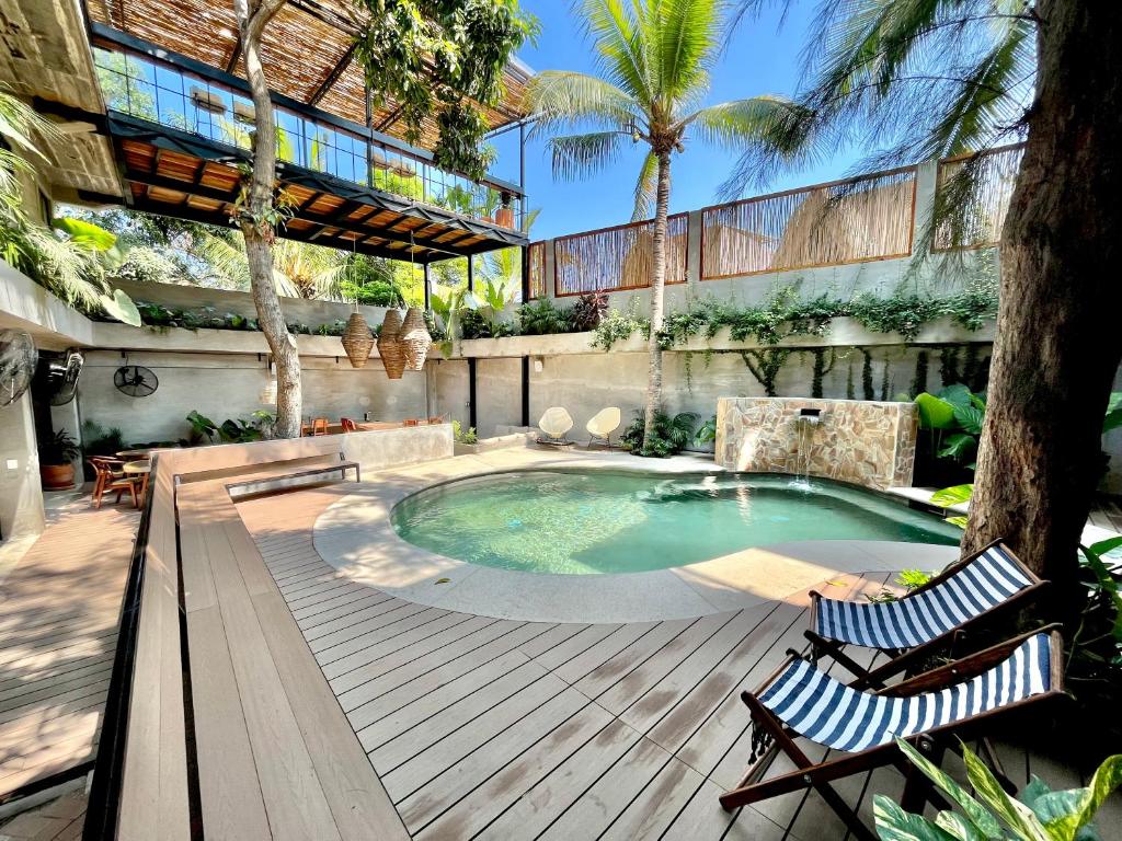 a swimming pool with two chairs on a wooden deck at Nectar Hotel, Cafe, Cowork - Adults Only in Puerto Escondido