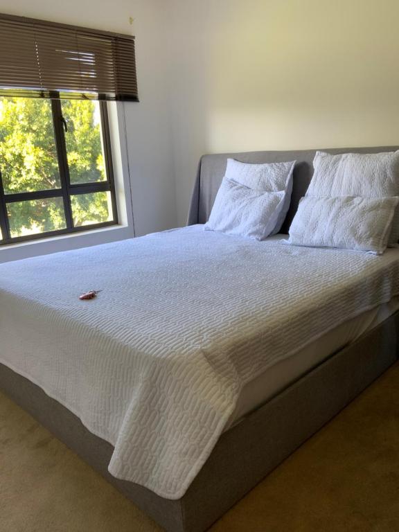 a bed with white sheets and pillows next to a window at G Gold BNB in Fourways
