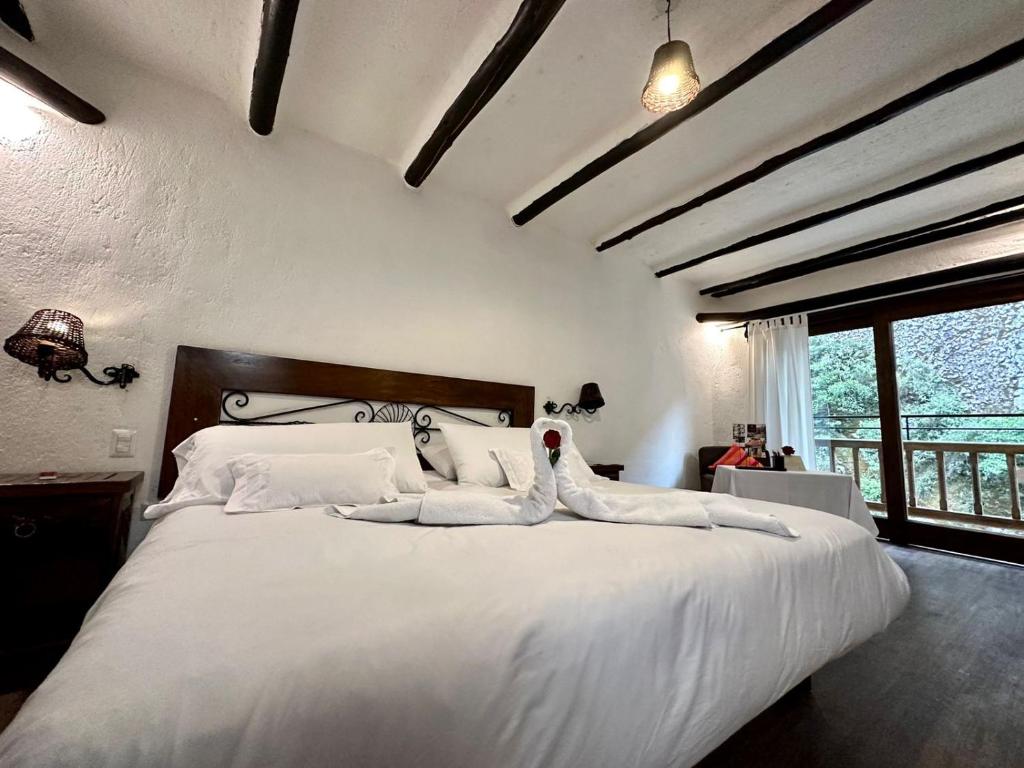 una camera da letto con un grande letto bianco con cuscini bianchi di Hatun Inti Boutique a Machu Picchu