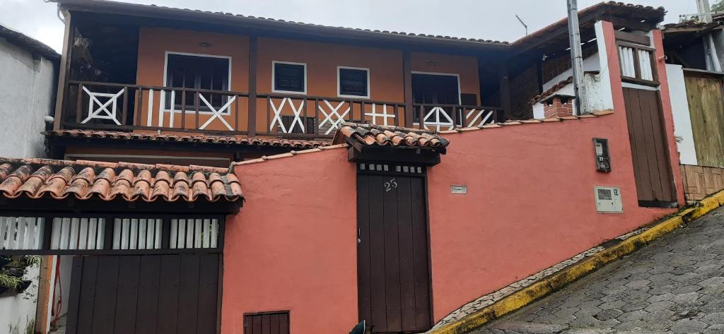 a red building with a gate and a balcony at Chalé do Radiola in Ilhabela