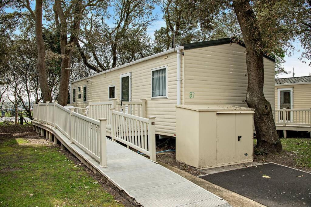 a white mobile home with a ramp next to a tree at Sandcastle Mobility Lodge in Christchurch